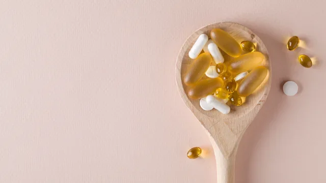 Health: supplements-herbs: supplements in wooden spoon pink background-1223933342