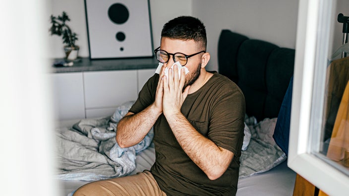 Man blowing his nose in bed