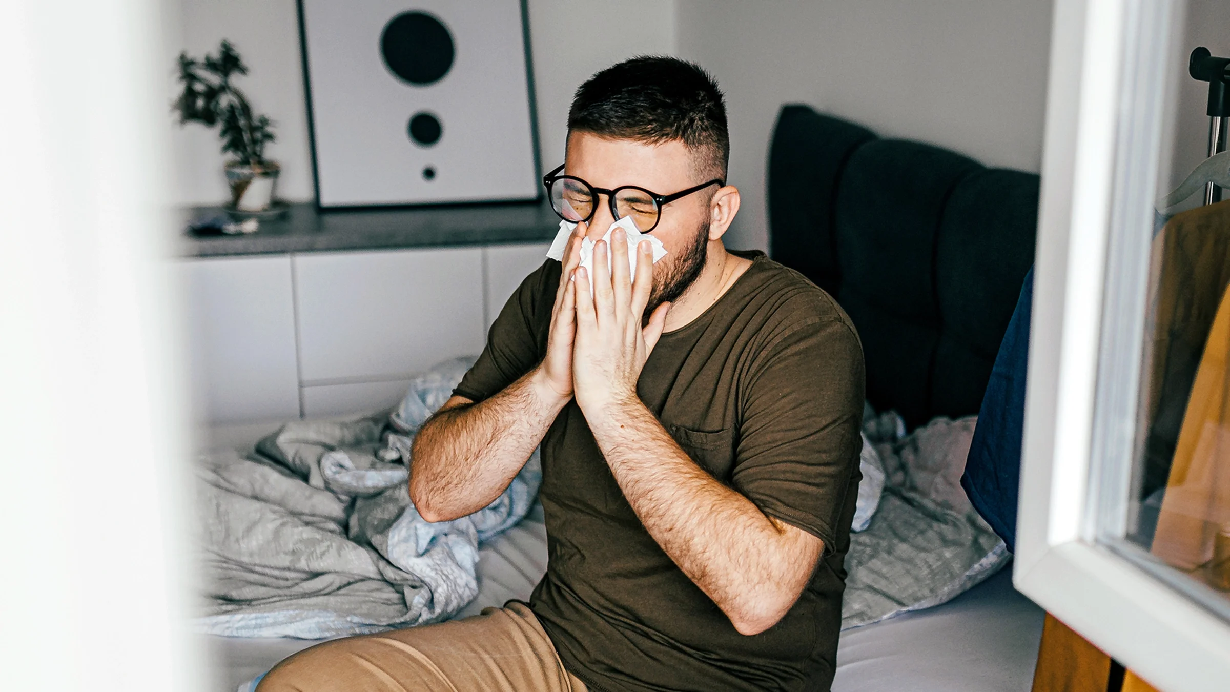 Man blowing his nose in bed