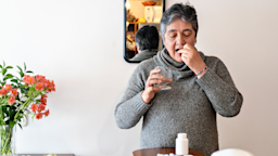 Woman taking a single pill with a glass of water. She is standing in front of a small mirror in her home.
RECVISUAL/E+ via Getty Images
