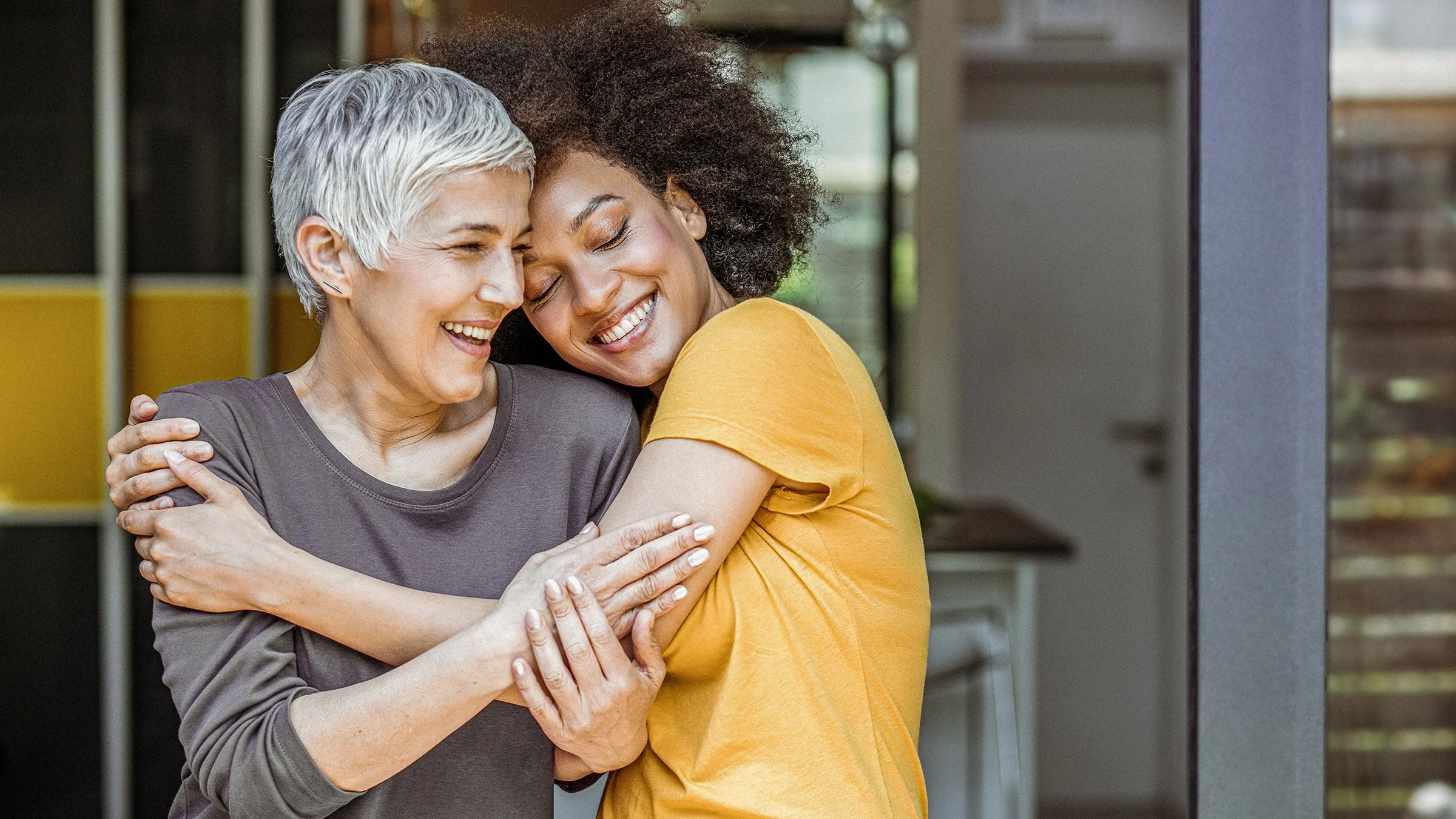 Two women hugging and smiling outside.
