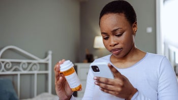 Pharmacy: woman researching medication on her smart phone 1480574597
