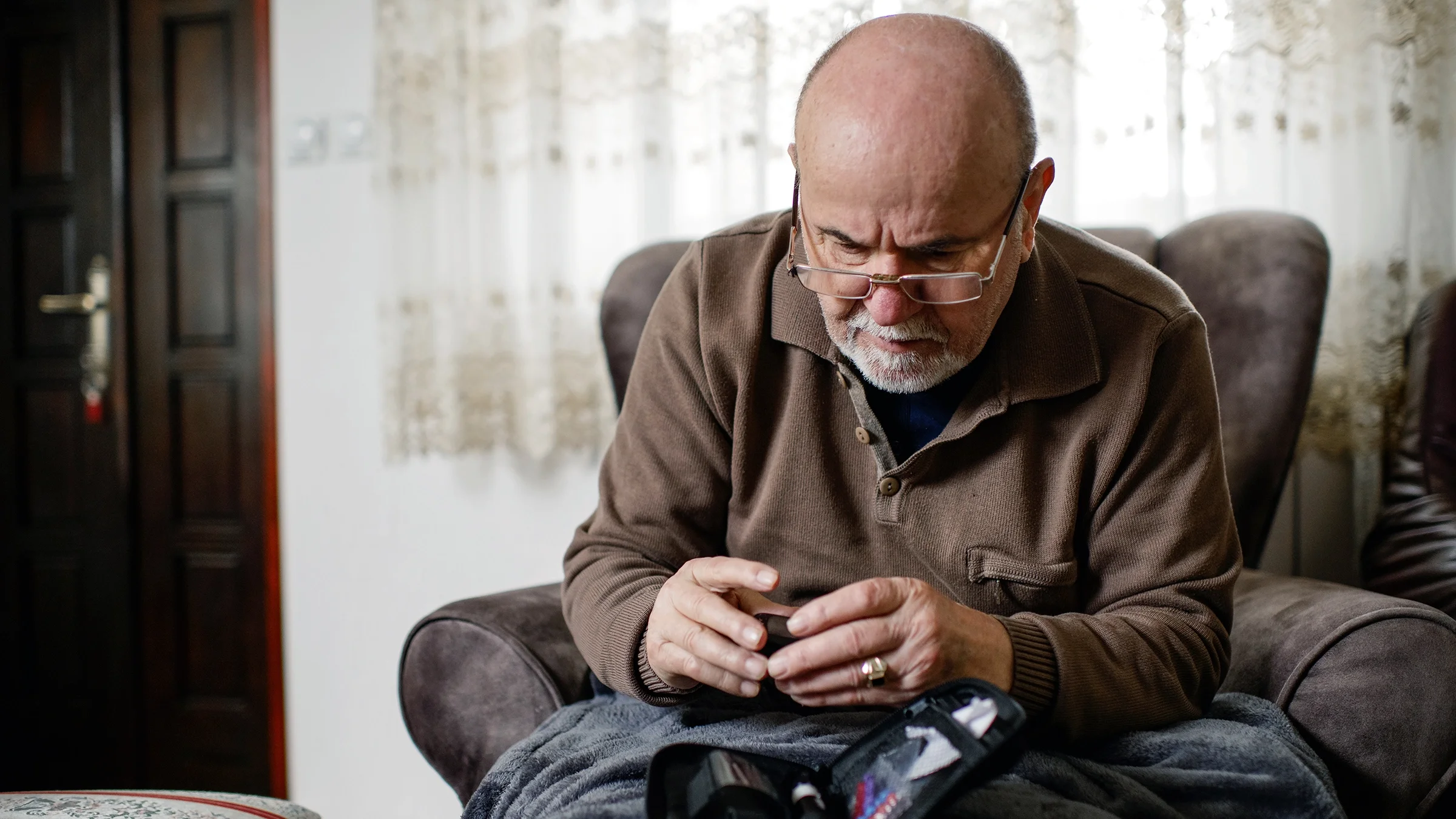 An older adult is checking their blood sugar level at home with a glucometer.