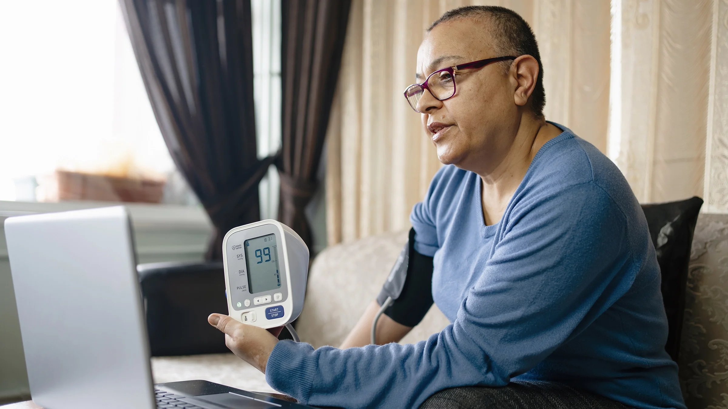 A patient takes her blood pressure during a virtual appointment.