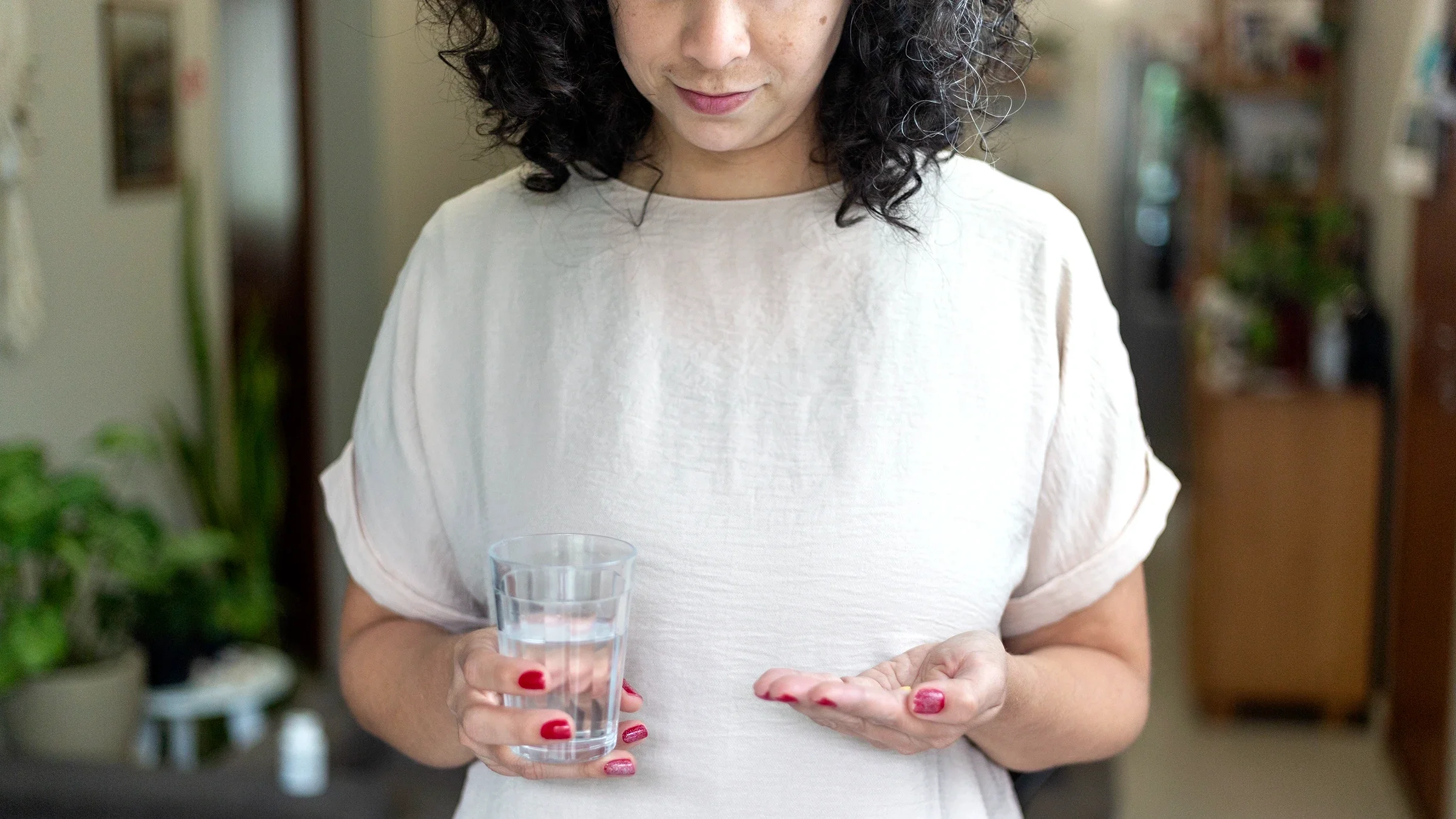A woman is taking medication with a glass of water.