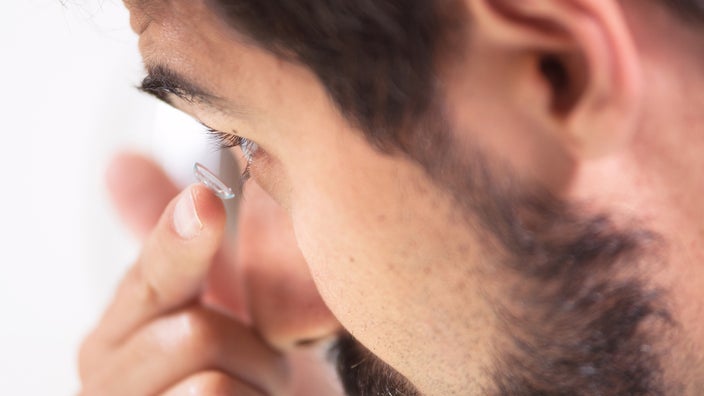 Close-up of a man putting in contact lenses.