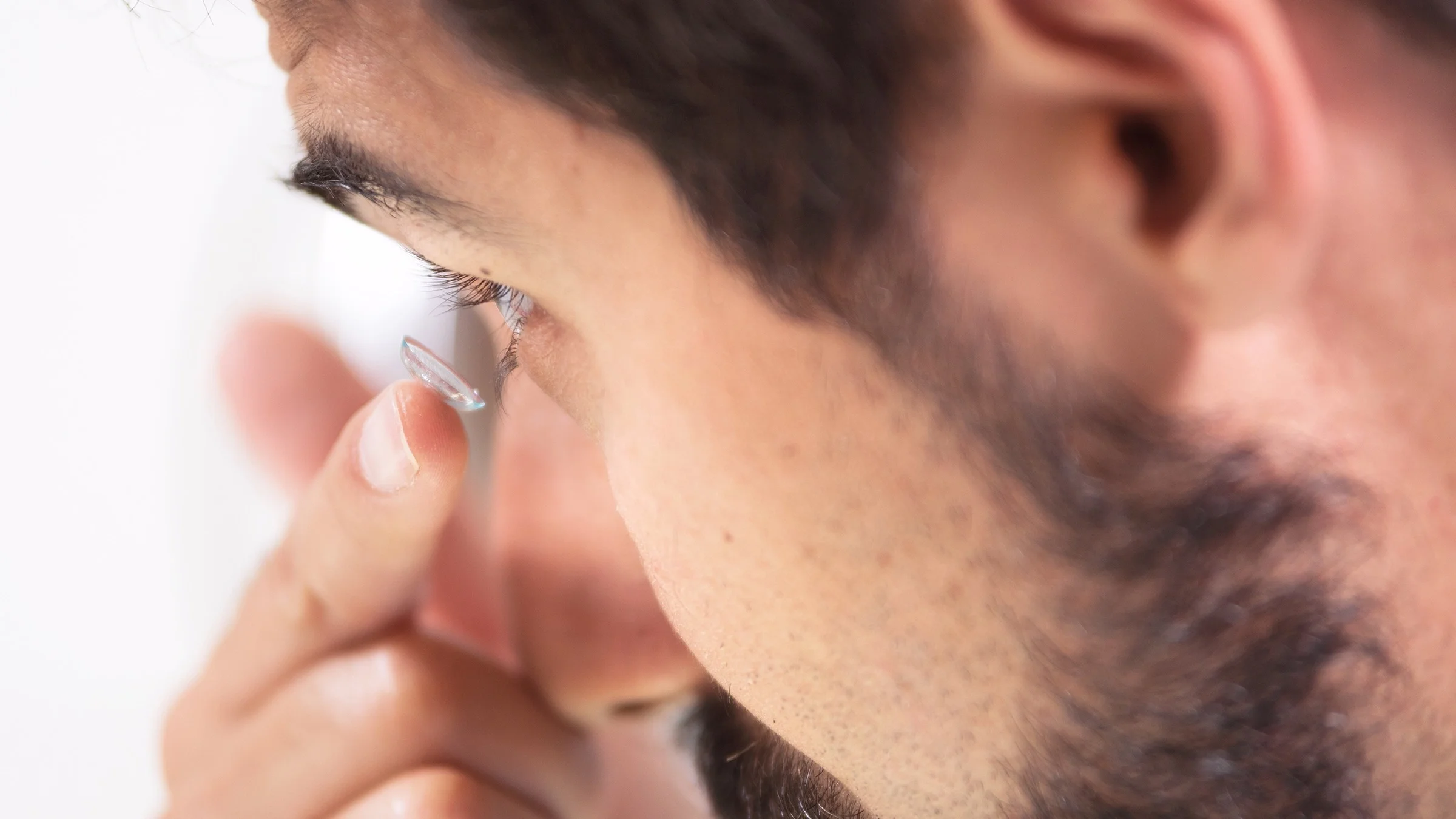 Close-up of a man putting in contact lenses.