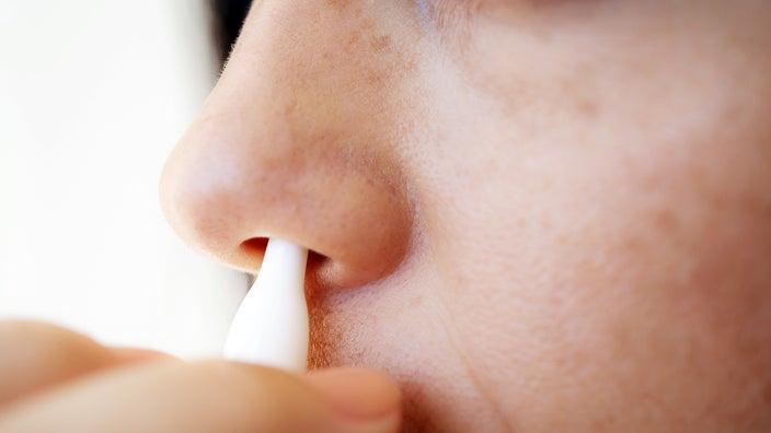 A woman uses nasal spray.