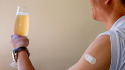 Cropped shot of someone holding a wine glass with a vaccinated arm which has a bandaid on it.
Cerise HUA/iStock via Getty Images
