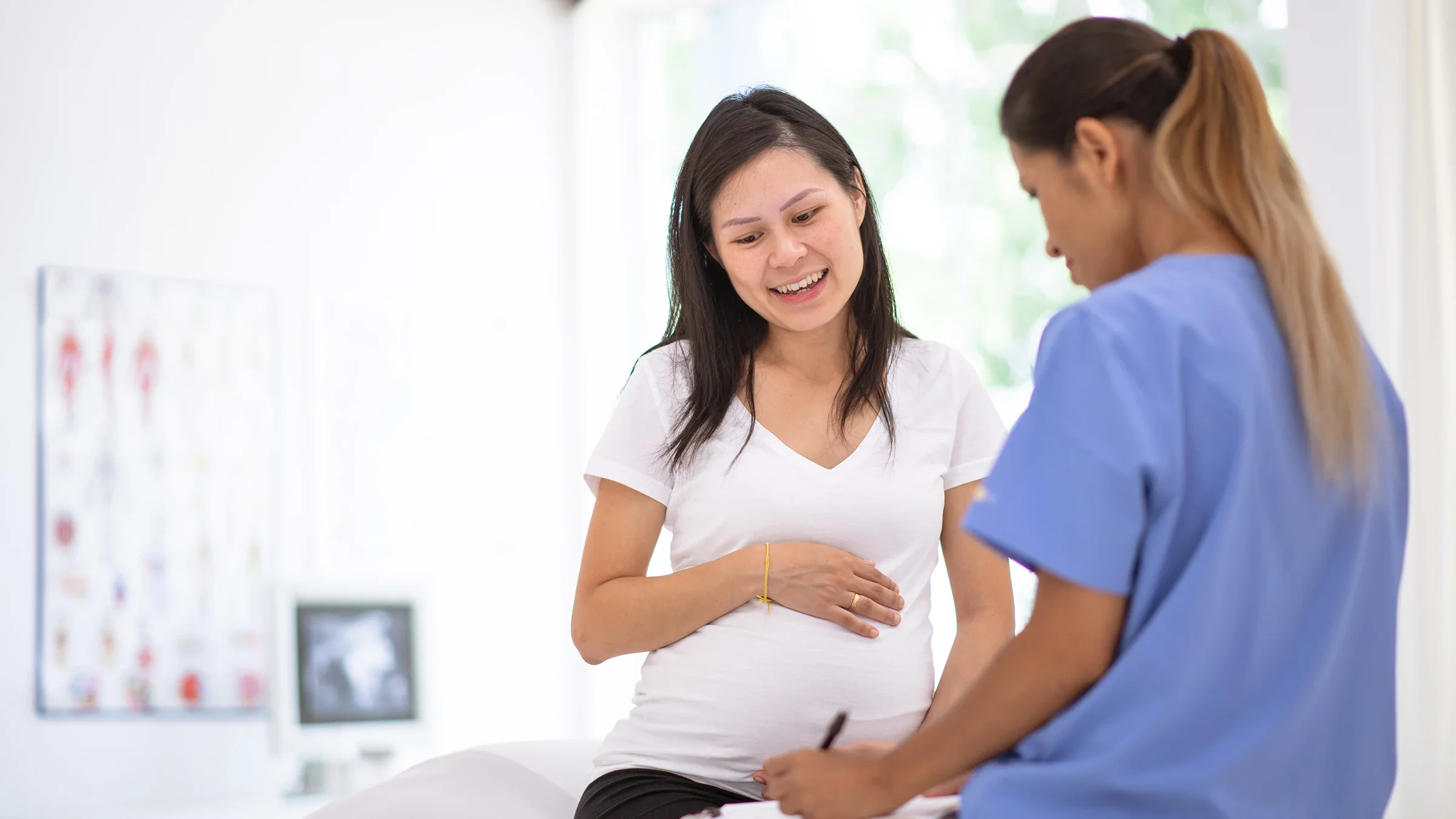 Pregnant woman with her doctor writing a prescription in the exam room.
FatCamera/iStock via Getty Image