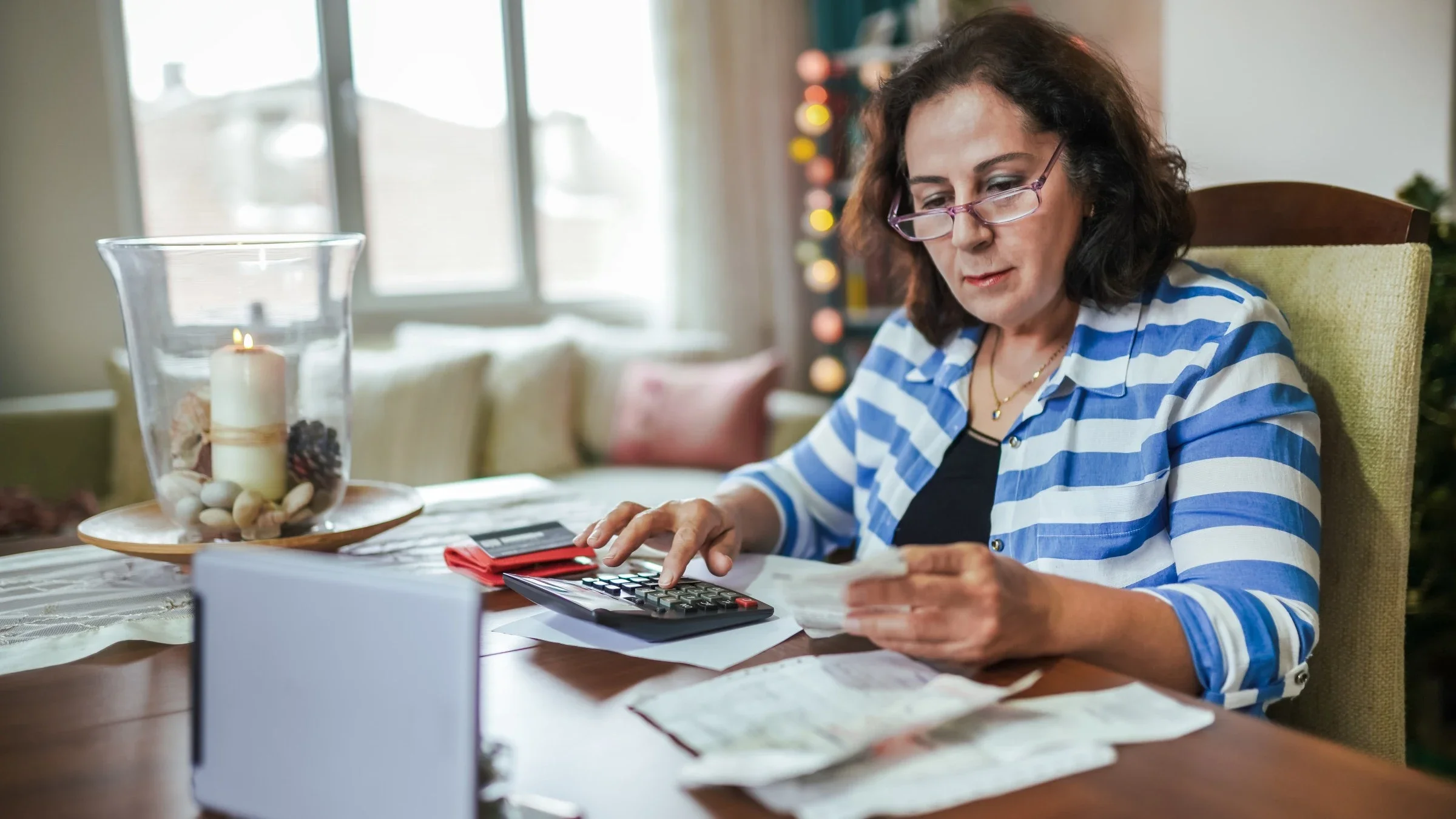 Senior woman sitting at the table with financial paperwork and a calculator.
Kemal Yildirim/E+ via Getty Images