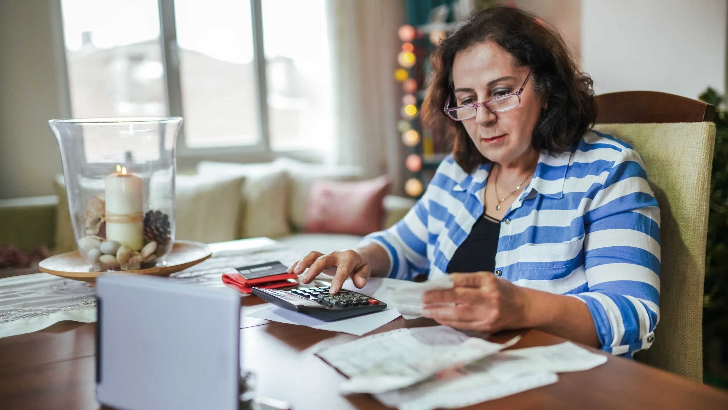 Senior woman sitting at the table with financial paperwork and a calculator.