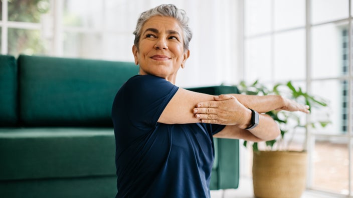 A woman does a cross-arm stretch.