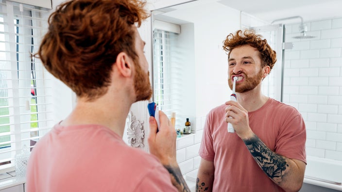Man brushing his teeth using an electric toothbrush.