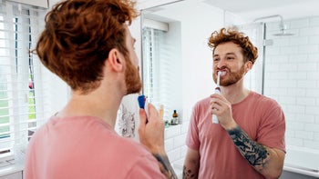 Dental-care: man brushing teeth with electric toothbrush 1820297429