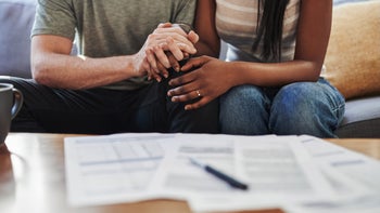 Abortion: Couple: cropped shot of couple holding hands while reviewing paperwork-1172498893