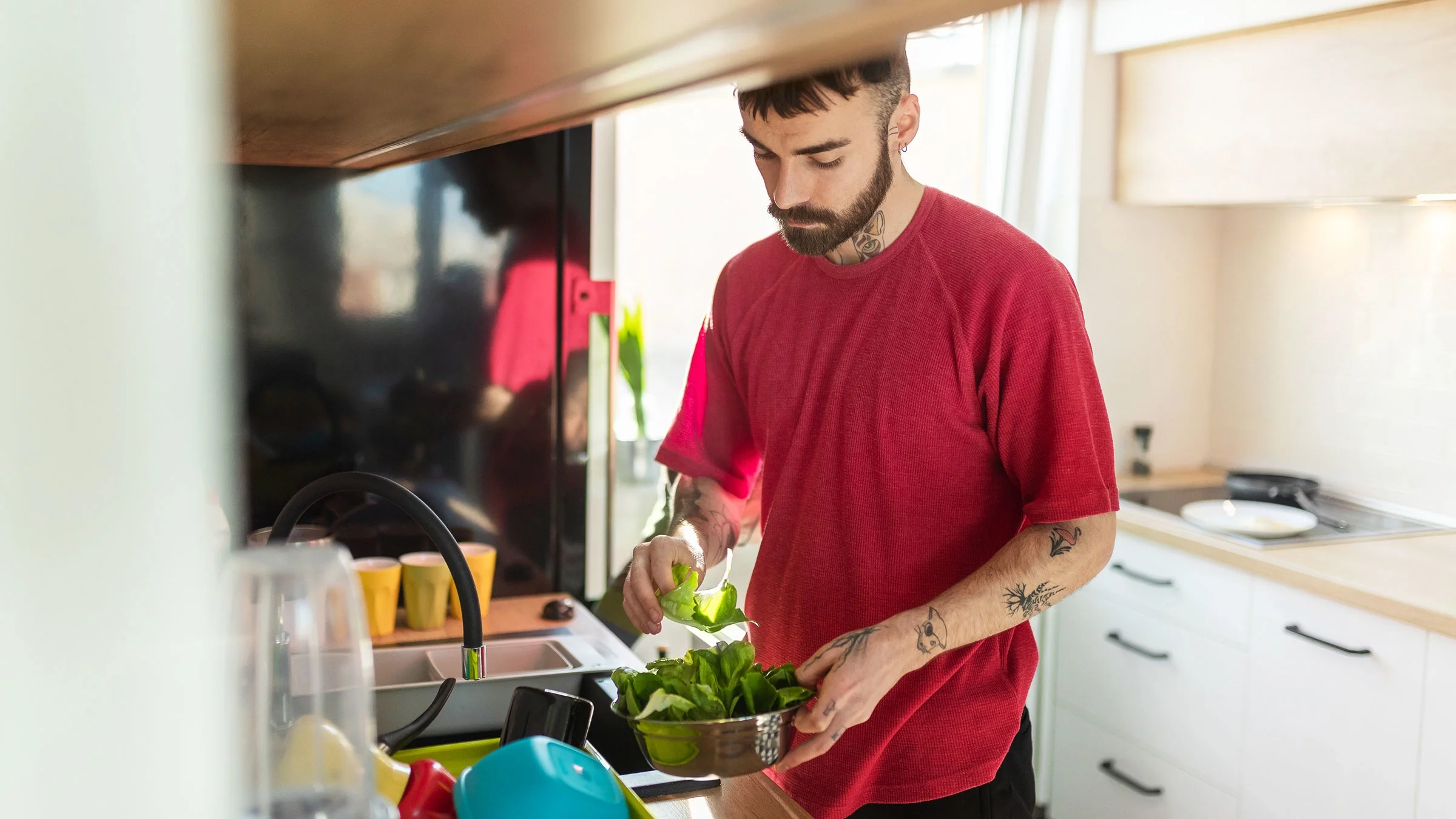 A man rinses leafy vegetables in the kitchen. Eating green leafy vegetables can help raise your iron levels before donating blood.