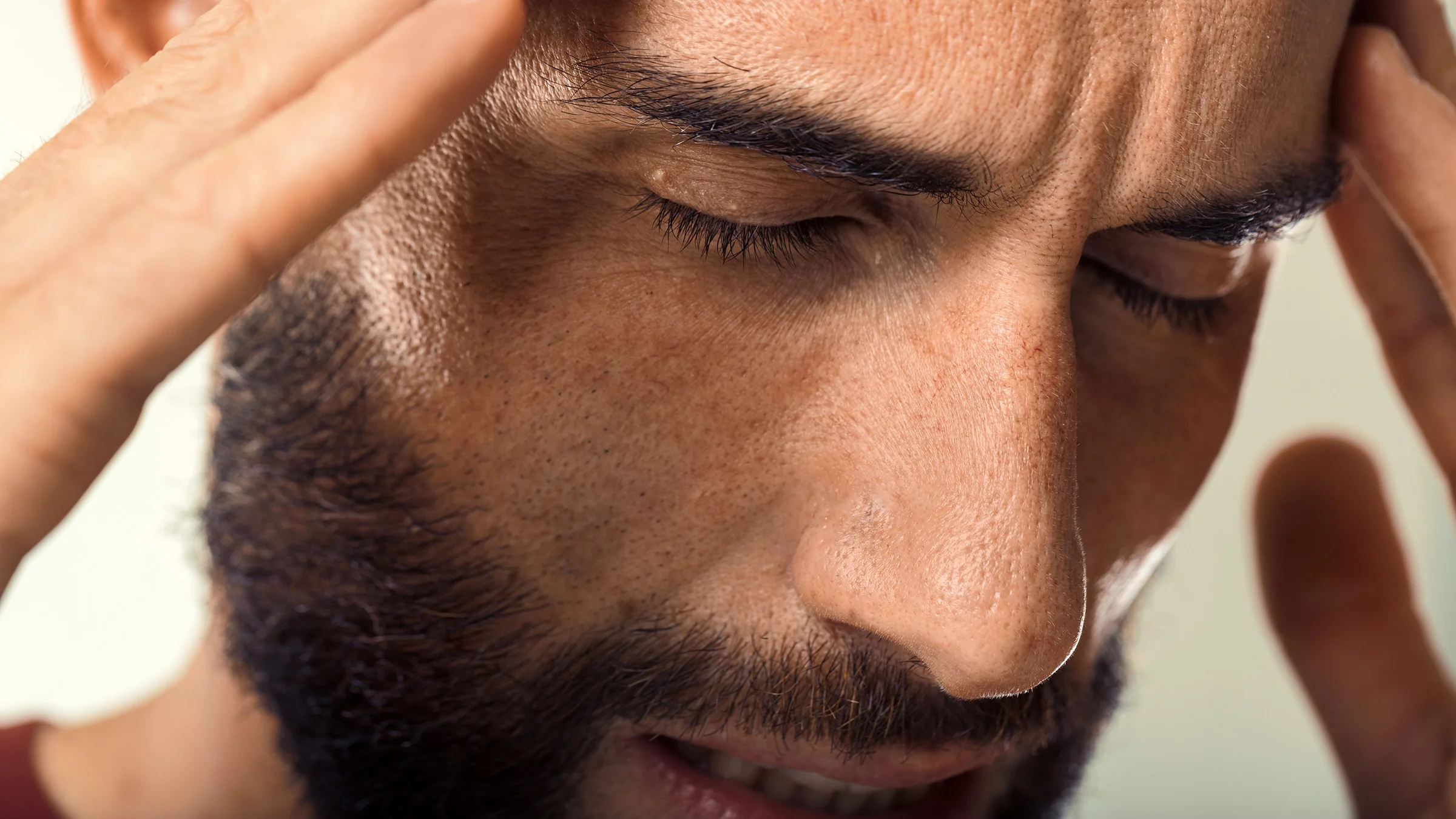 Man touches his forehead with pained expression