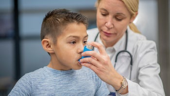Asthma: child using asthma inhaler 1199989919