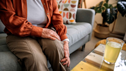 A woman sits on a couch and holds her leg in pain.
eclipse_images/E+ via Getty Images
