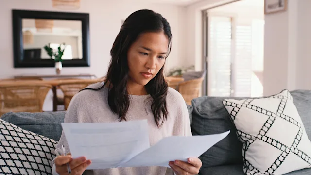 FSA HSA: woman reviewing paperwork at home 2181519924