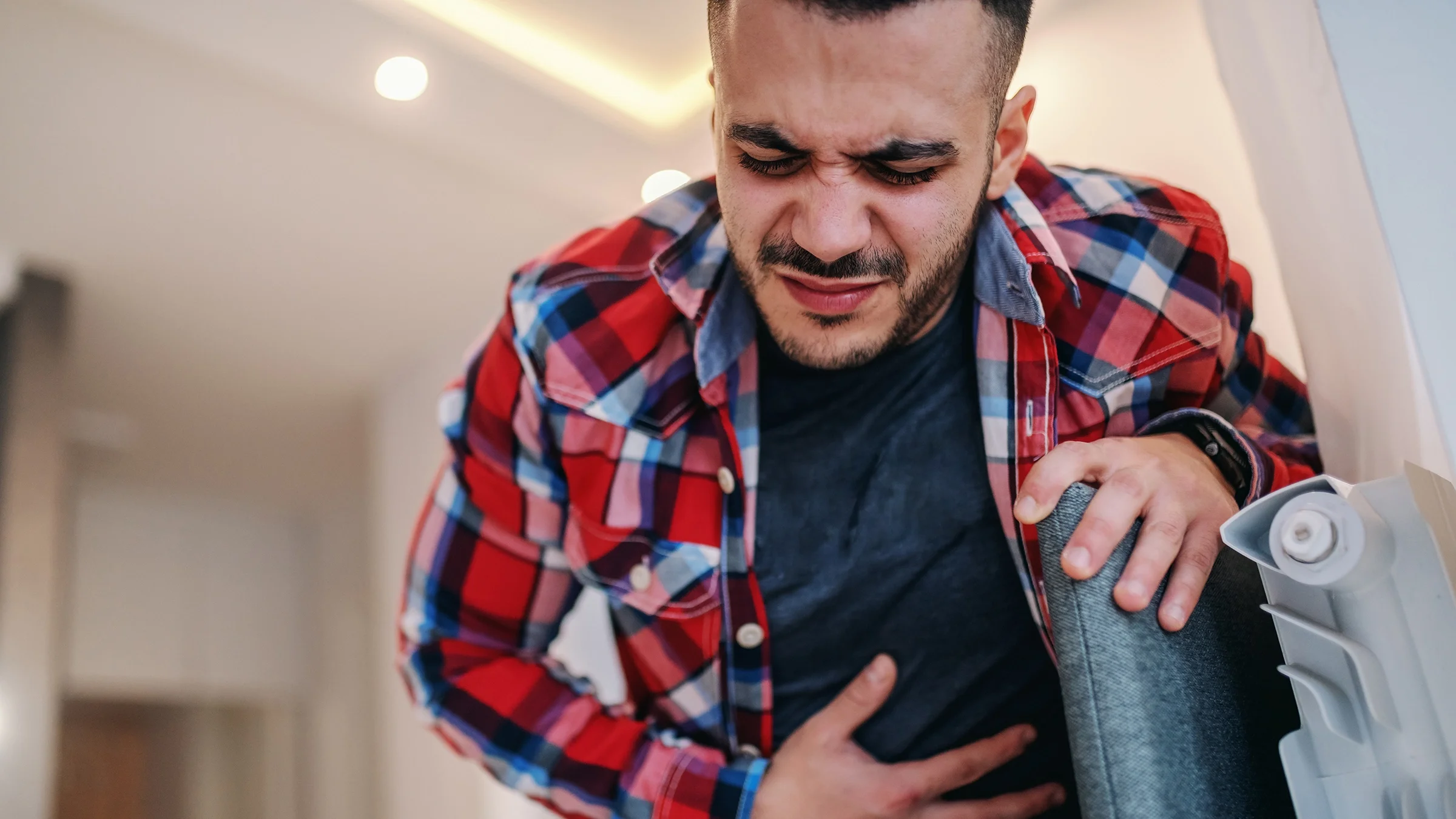 A man holds his belly as he experiences stomach pain.