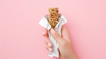 Health: Diet and nutrition: hand granola bar on pink 1173552196
