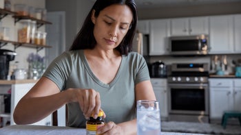 iron supplement: woman opening vitamin supplements 1345548001