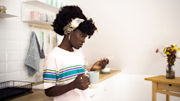 A woman takes her medication in her kitchen.
MixMedia/E+ via Getty Images