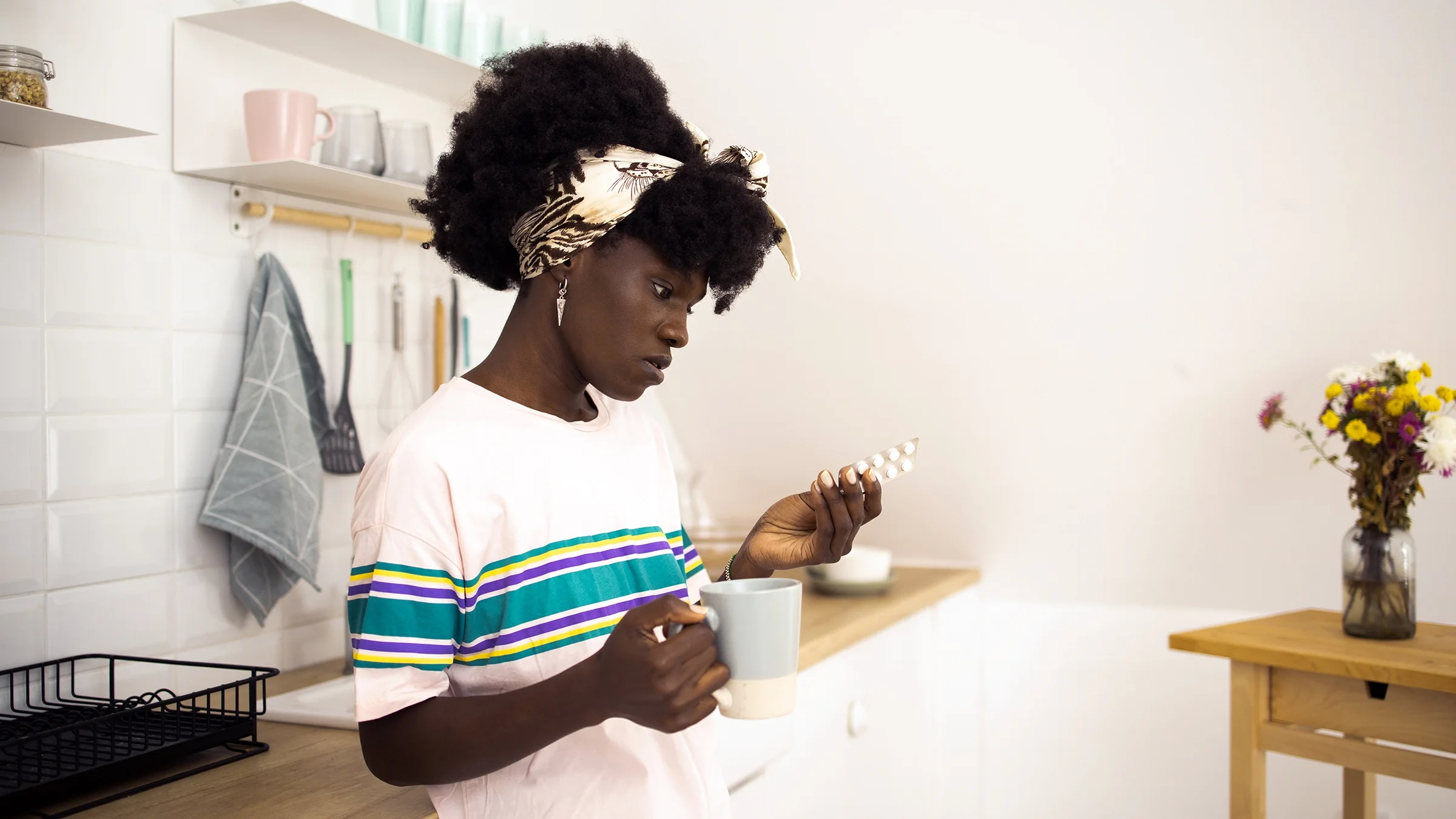 A woman takes her medication in her kitchen.