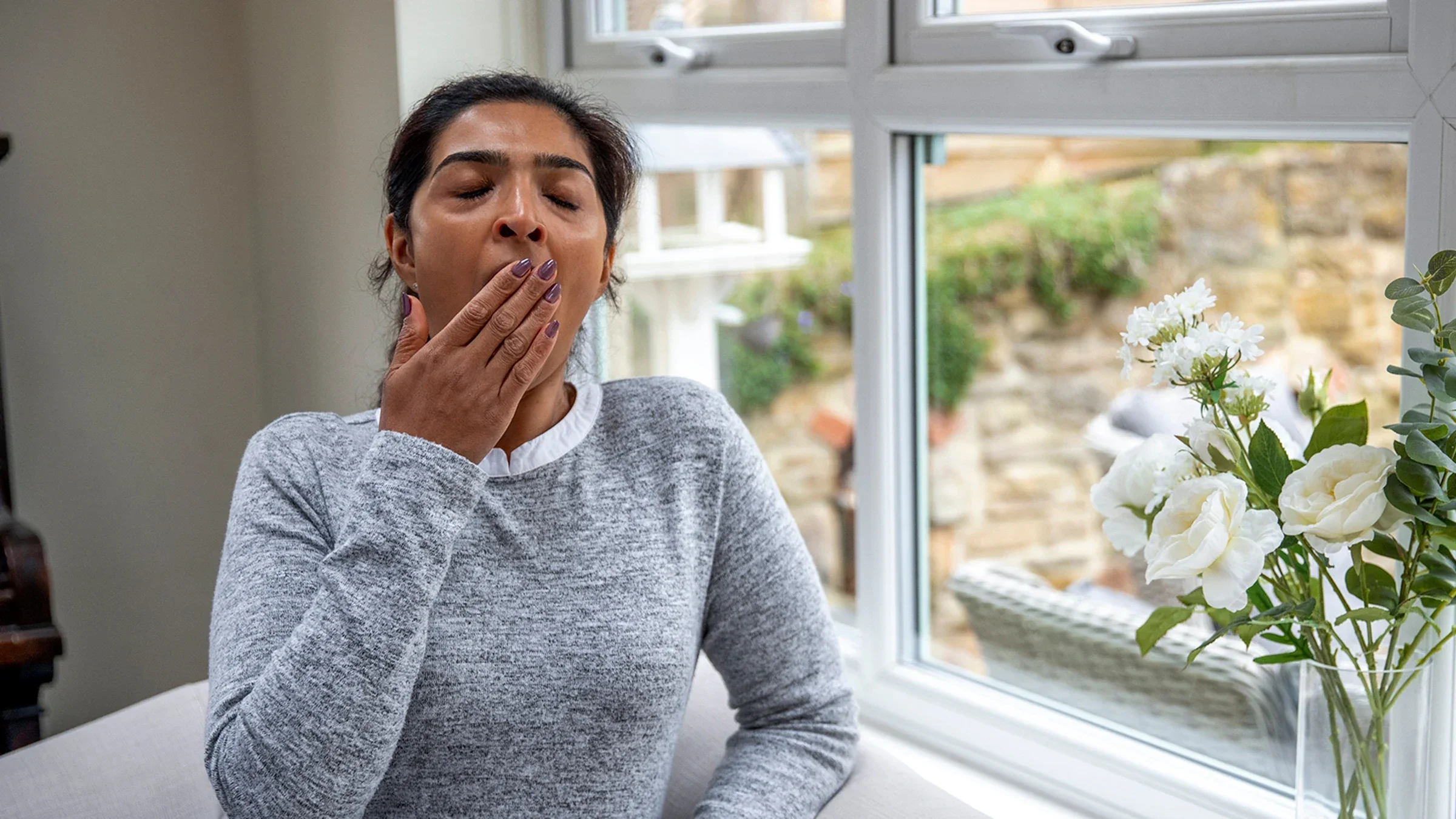 A woman suffering from daytime sleepiness yawns and covers her mouth.
SolStock/E+ via Getty Images 