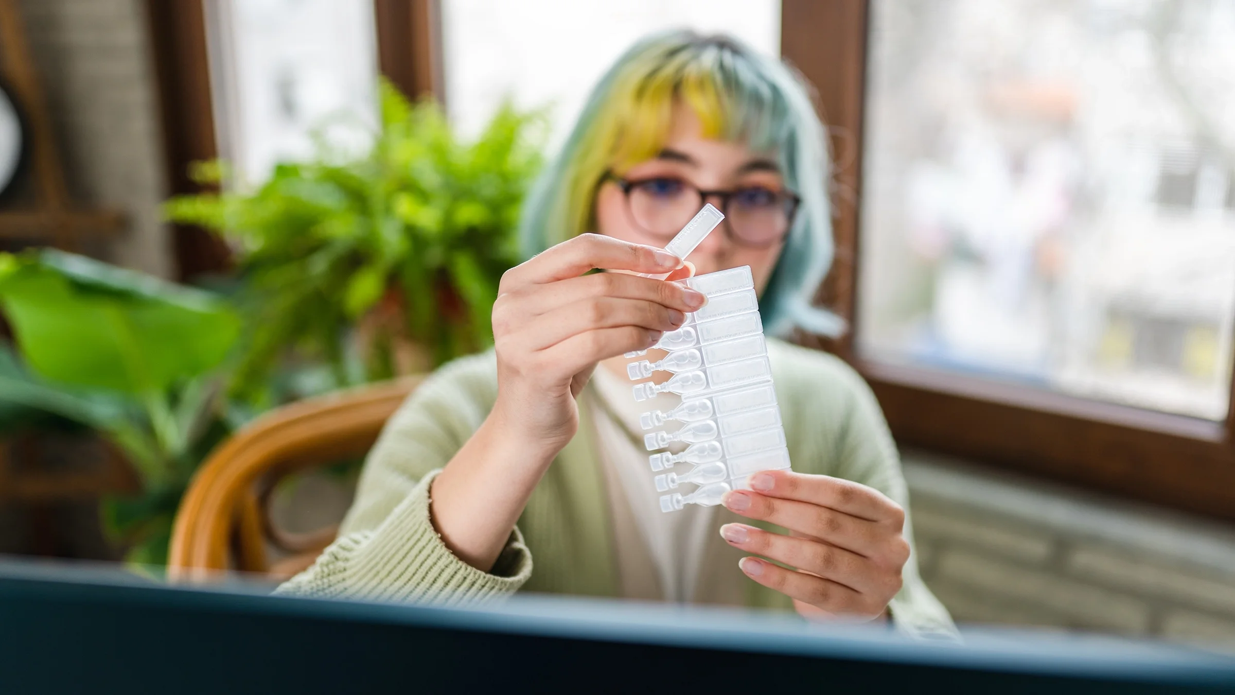 A woman prepares to administer a dose of eye drops.