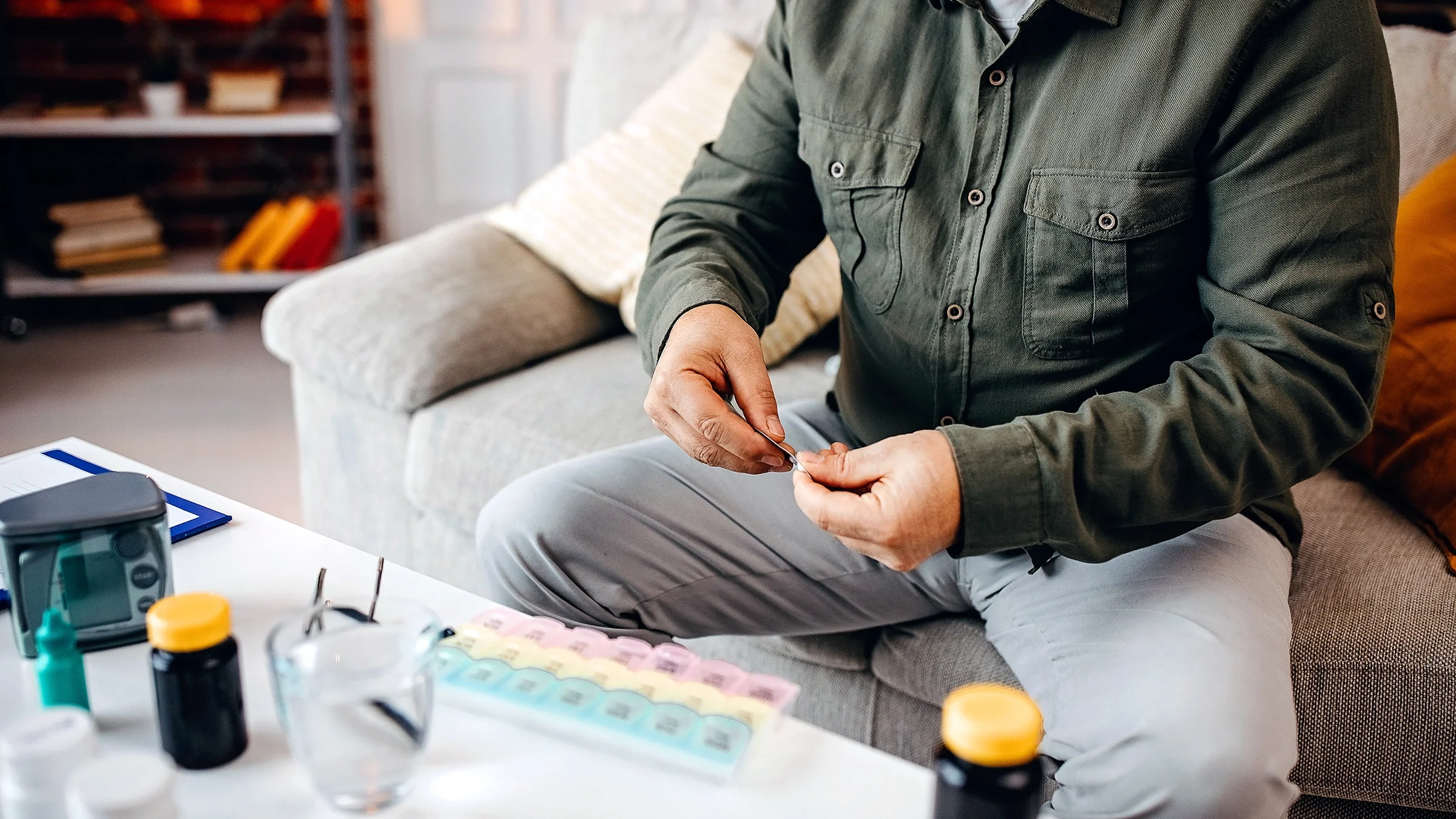 A man is organizing his medication in a pill dispenser.