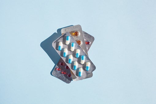 Multiple blister packs of various pills for flu treatment on light blue background.