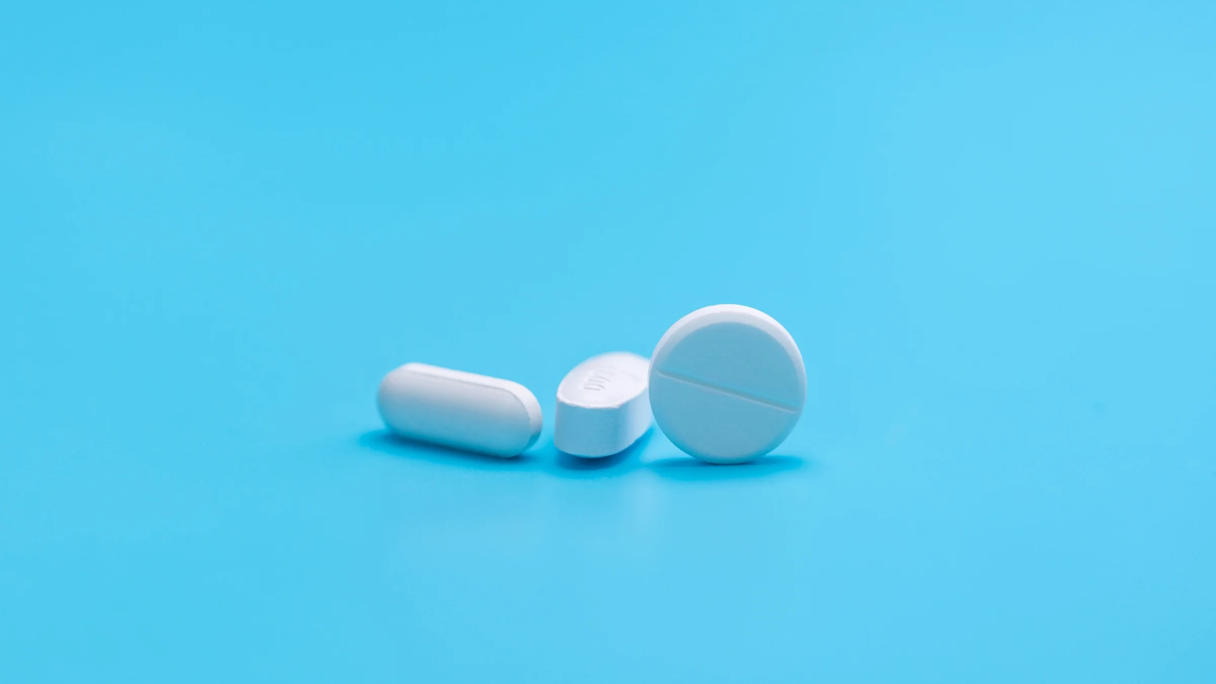 White pills on a teal background.