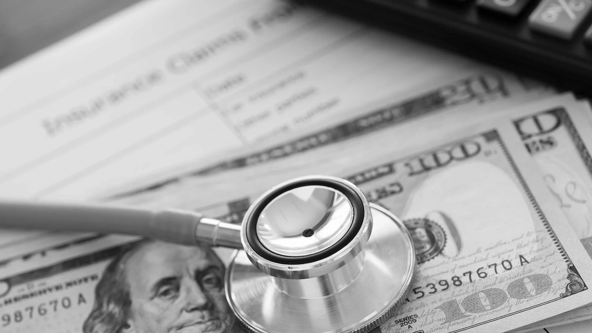 Close up on a stethoscope resting on top of paperwork and a pile of cash.
utah778/iStock via Getty Images