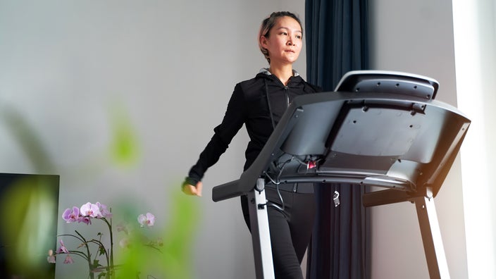A woman is exercising on a treadmill in a home gym.