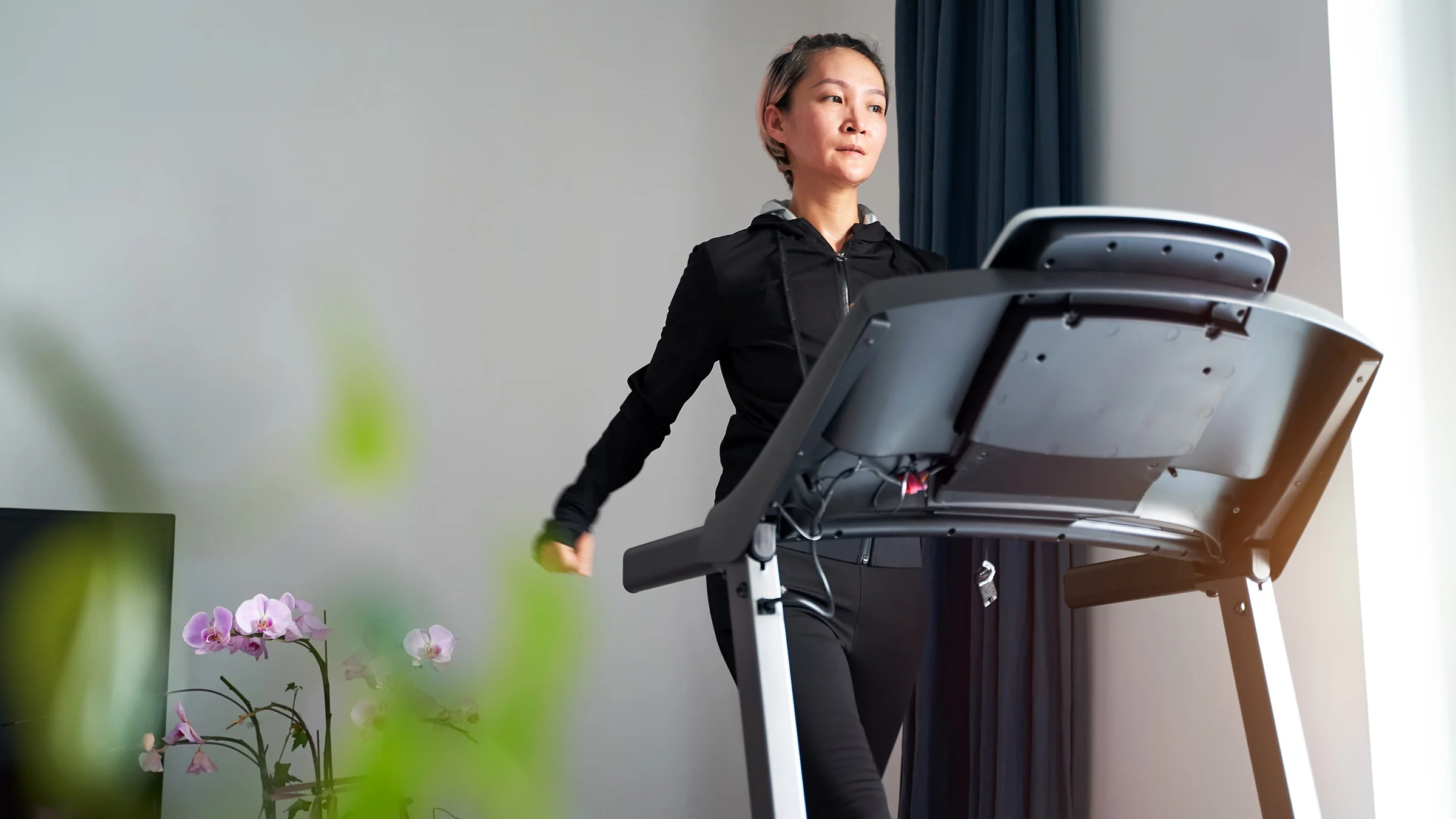 A woman is exercising on a treadmill in a home gym.