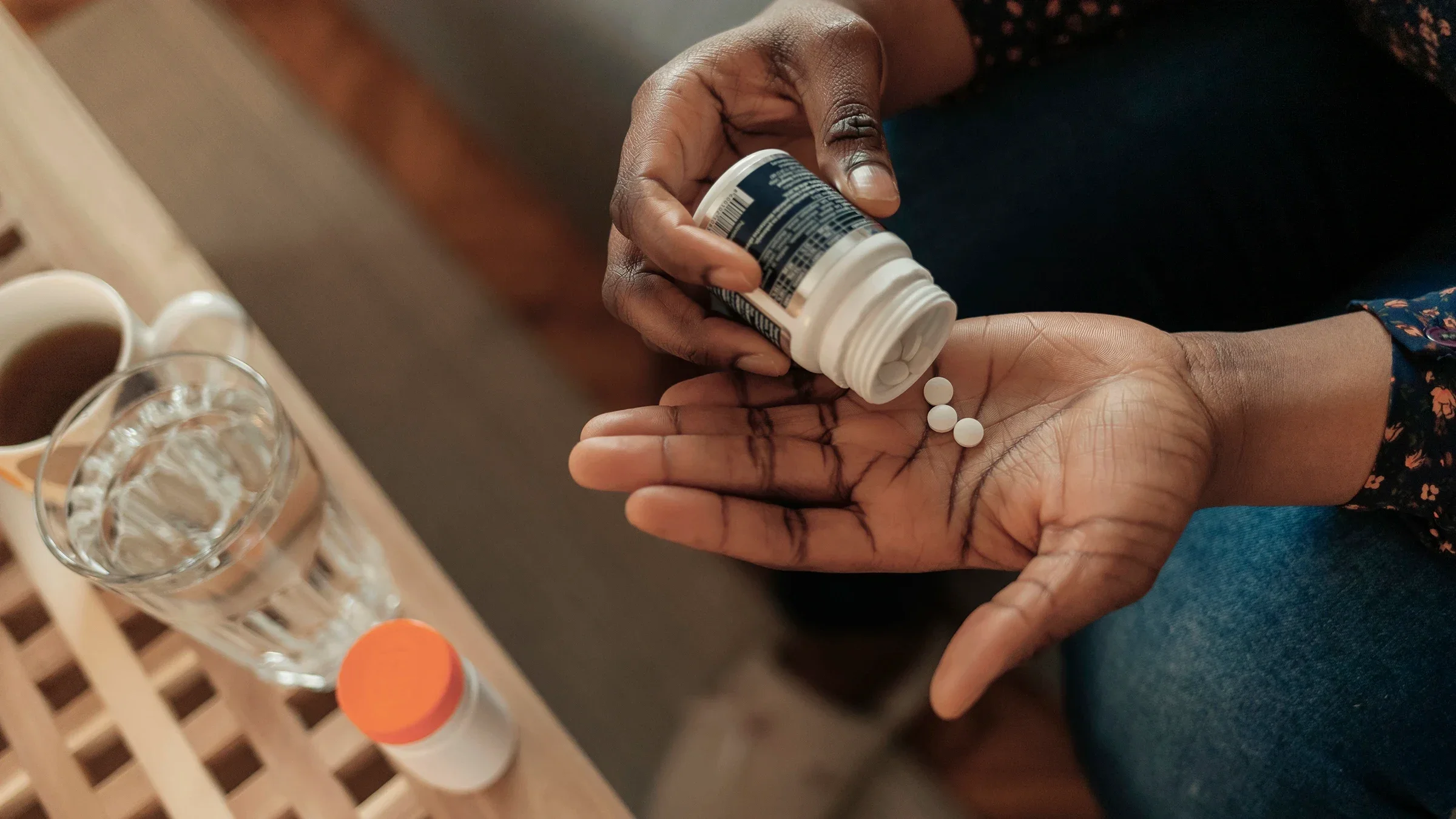 Cropped overhead shot of a woman pouring pills into her hand from a pill bottle.
PixelsEffect/E+ via Getty Images