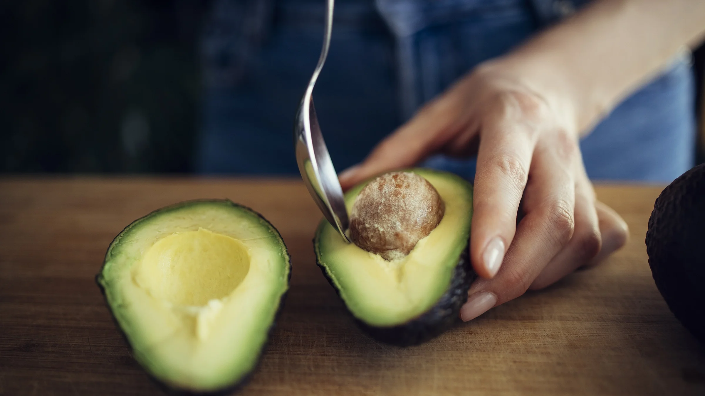 A close-up of a person removing an avocado pit.