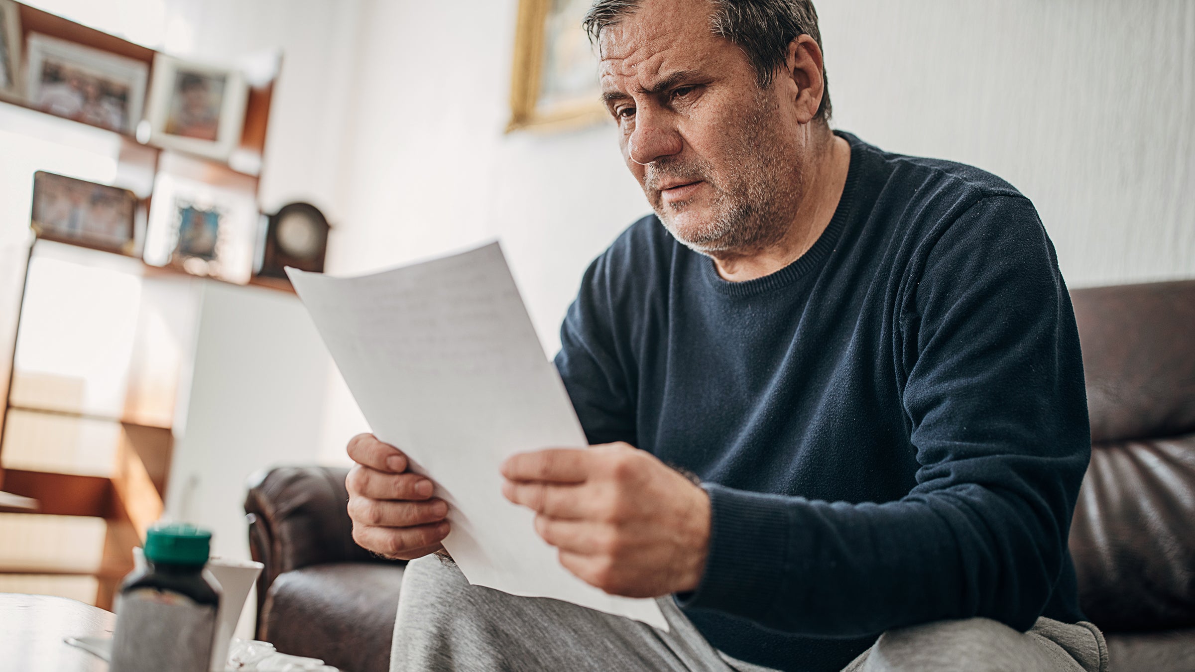 Middle-aged man worried as he reviews his medical bills at home.