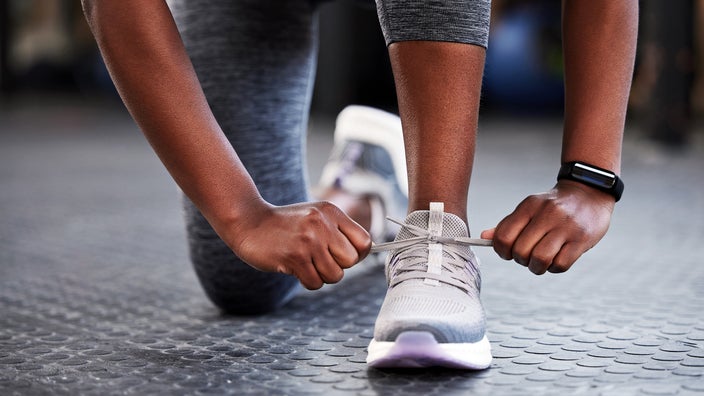 A woman ties the shoelaces on her running shoes.