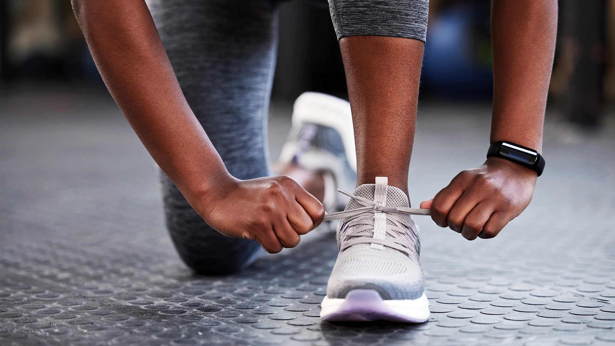 A woman ties the shoelaces on her running shoes.