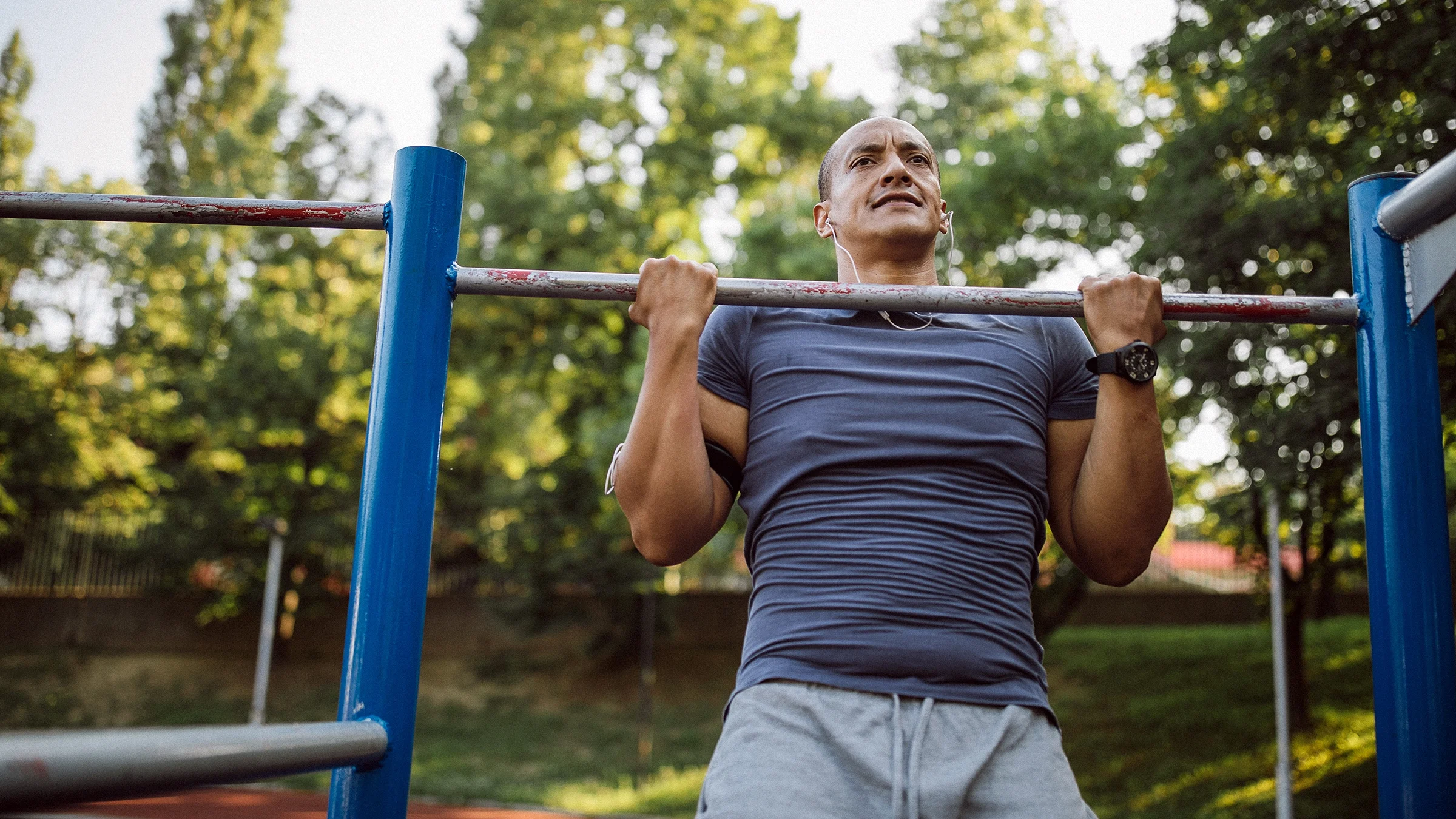 A man does pull-ups in the park.