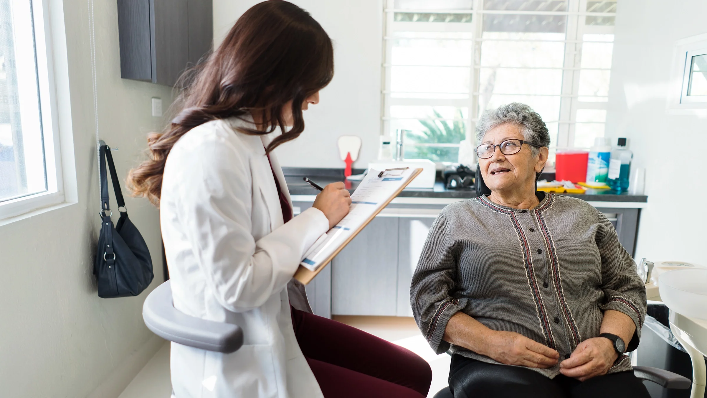 A dentist talks to a senior patient.
