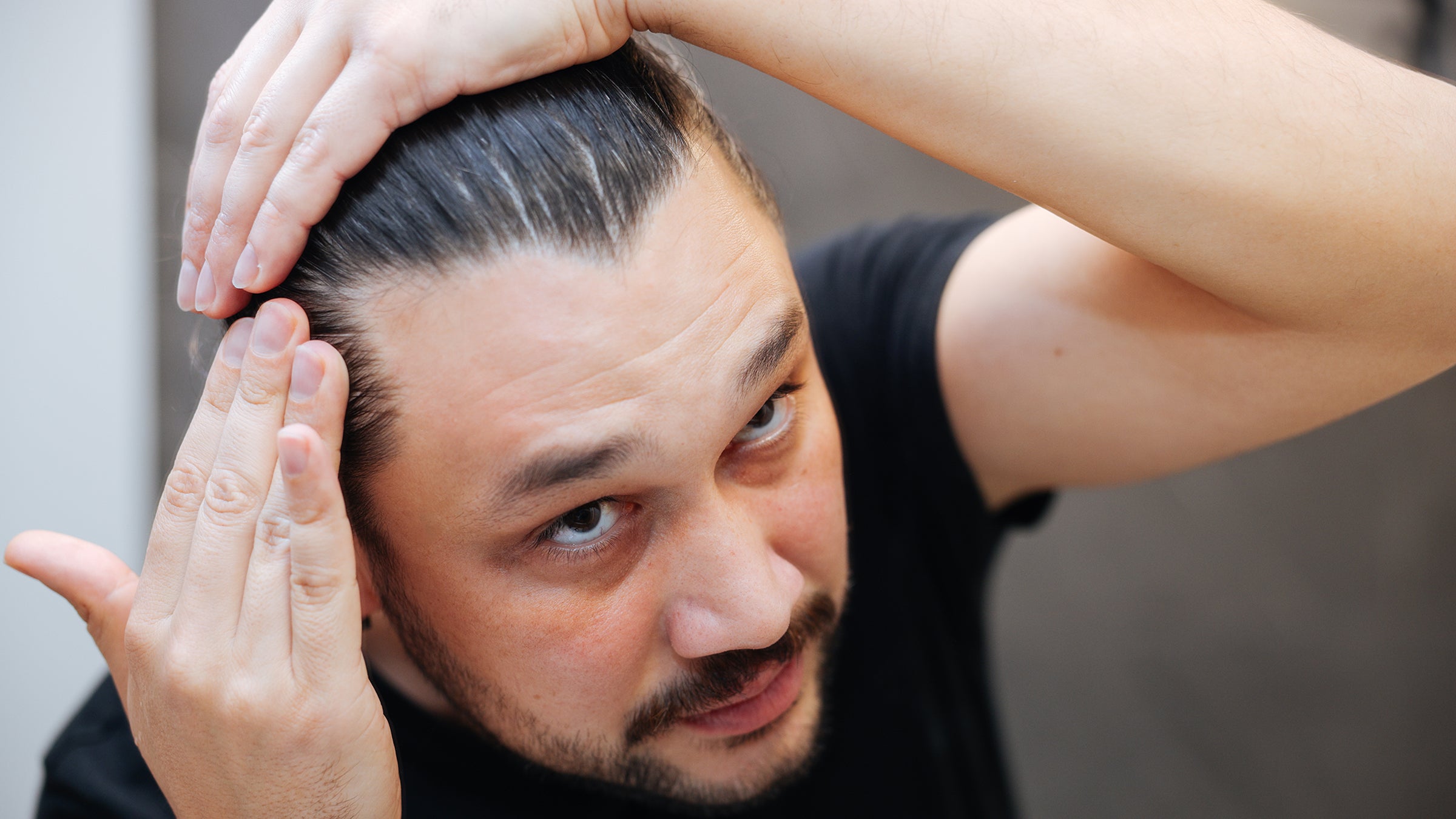 Hair loss: man checking hairline in mirror 2138687486