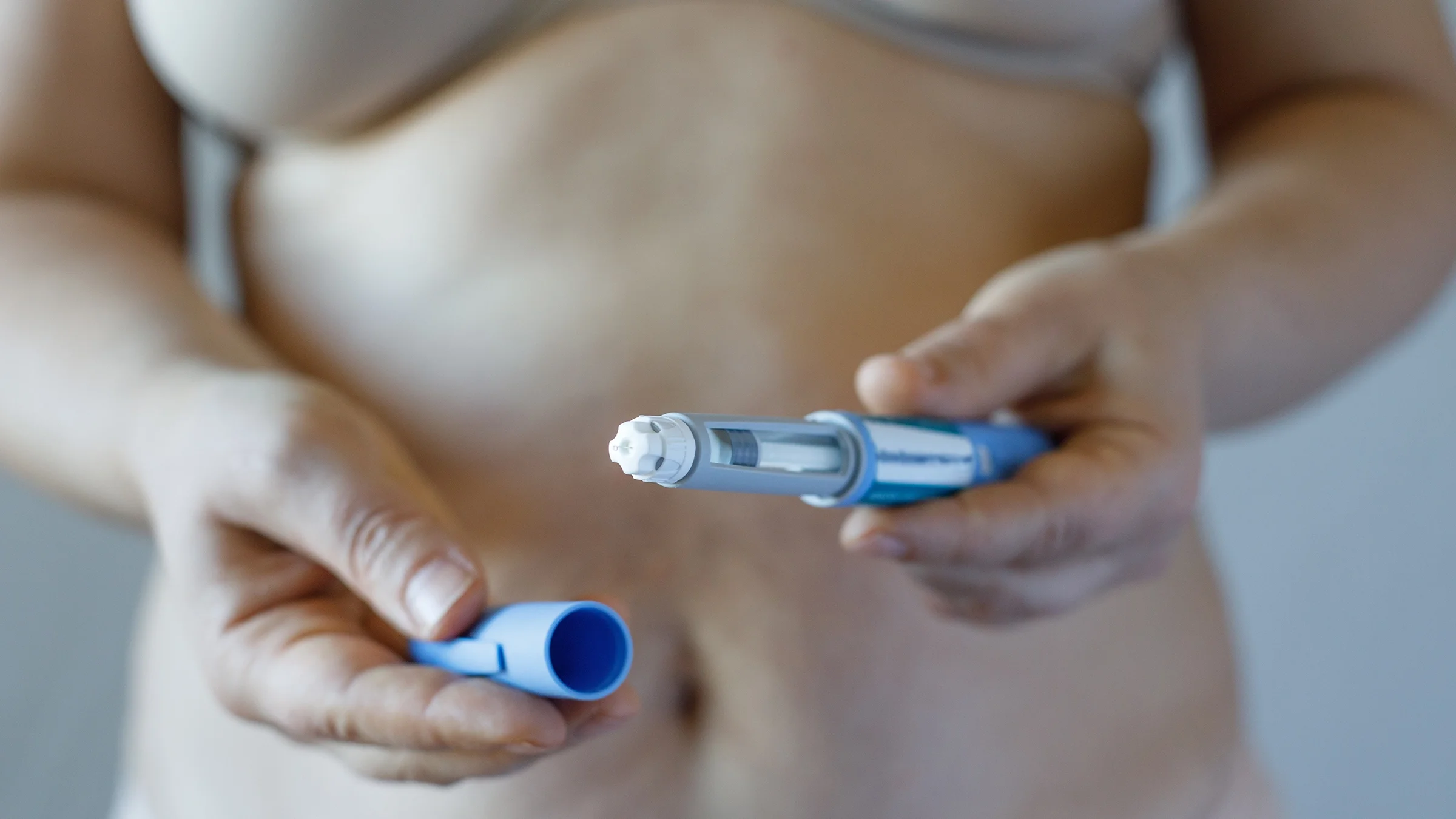 A woman holds an injection pen.