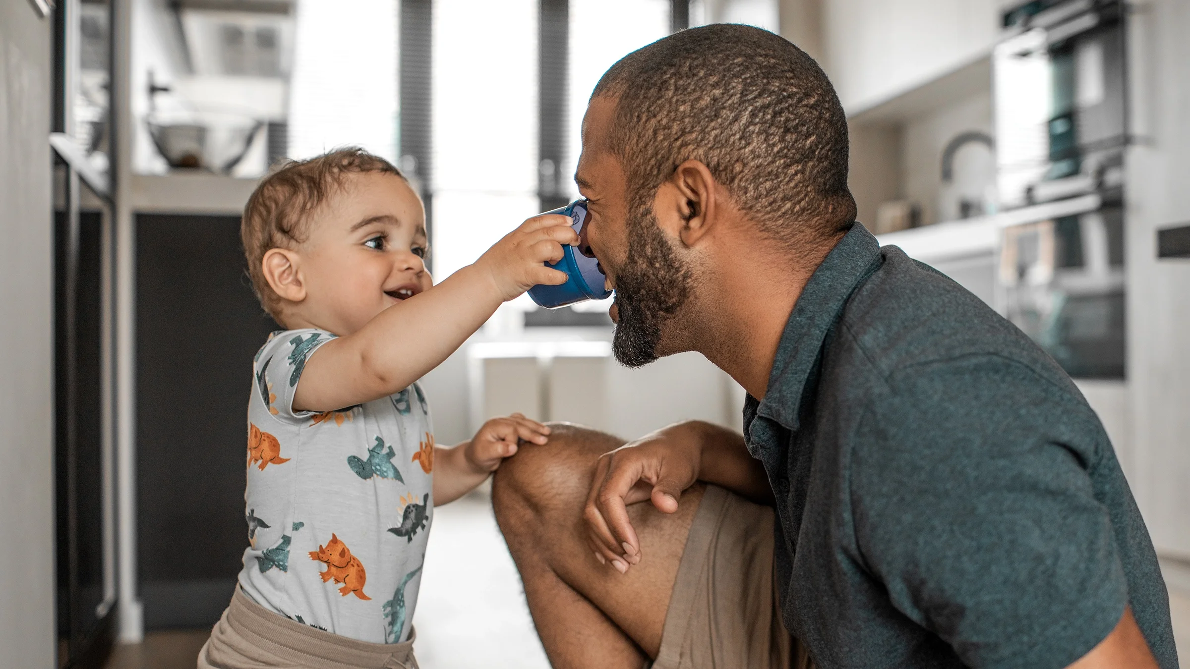 A father plays with his toddler at home.