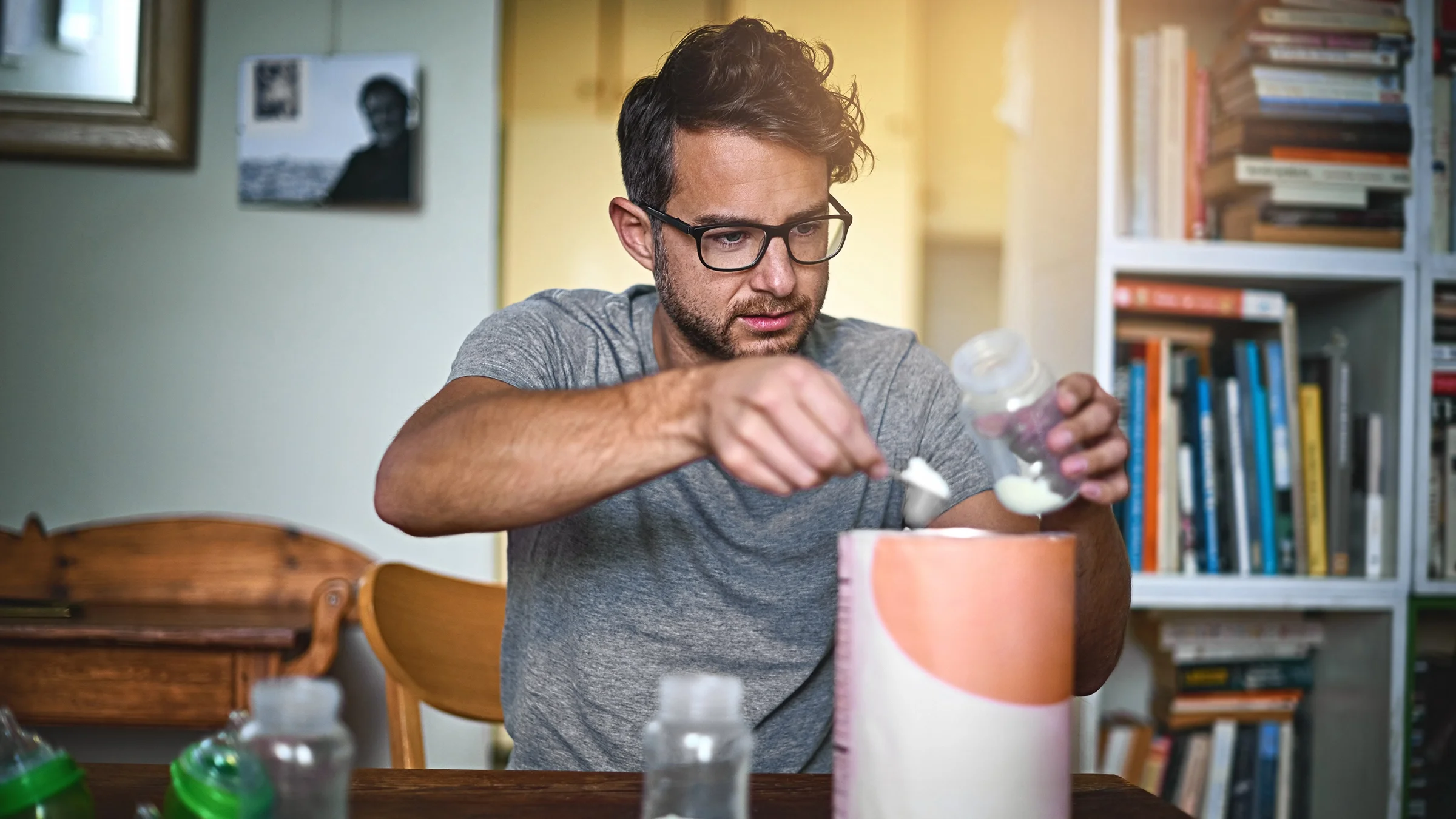 A father measures and pours baby formula into a bottle.