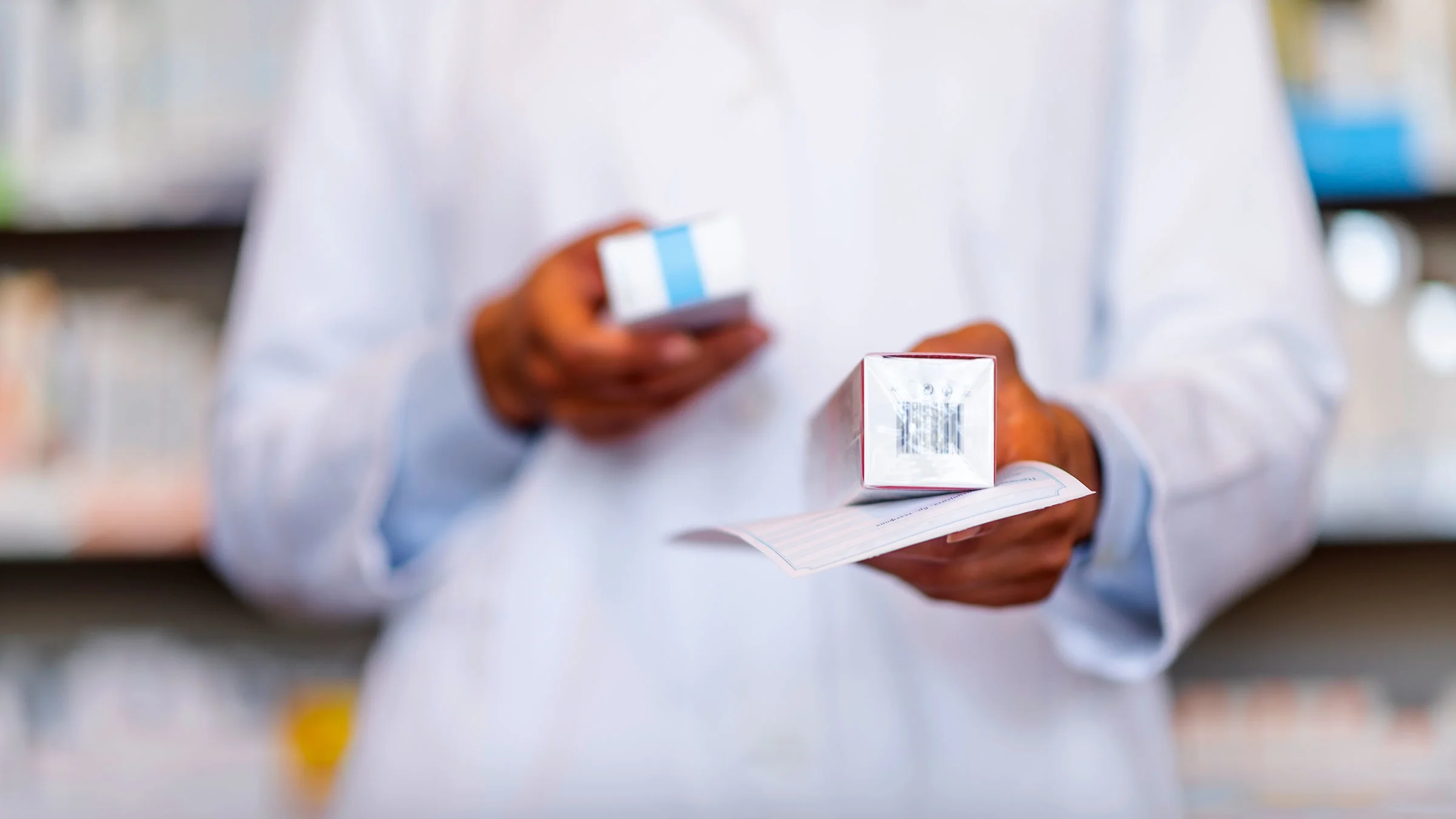 A pharmacist holds a prescription at a drugstore.